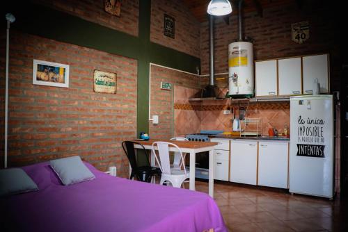 a kitchen with a bed and a table and a refrigerator at Cabañas Los Lúpulos in El Bolsón