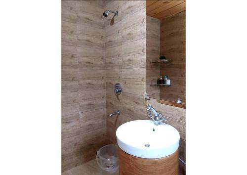 ビムタルにあるWhistling Thrush Chaletの白い洗面台と木製の壁が備わるバスルーム