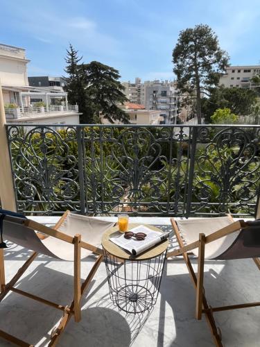 a balcony with a table with a drink on it at Hotel Alexandra - Boutique Hotel in Juan-les-Pins