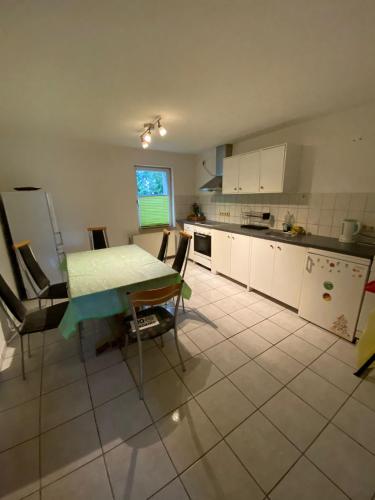 una cocina con mesa y sillas y una cocina con armarios blancos. en Ferienwohnung Wendischbrome en Jübar