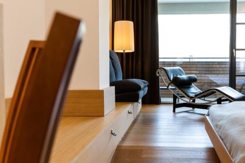 a bedroom with a bed and a chair and a tv at Bio & Wellnesshotel Pazeider - Healing Garden above Meran in Marlengo