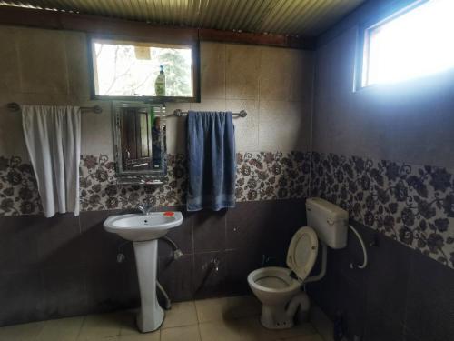 a bathroom with a sink and a toilet and a window at Evergreen Café in Kalgha