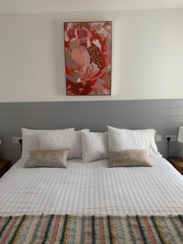 a white bed with pillows and a painting above it at Racecourse View in Listowel