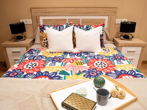 uma cama com um edredão colorido com uma bandeja em Precioso apartamento en el centro de Aviles em Avilés