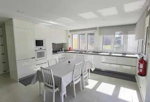 a kitchen with white cabinets and a table and chairs at Encanto de Arcos de Valdevez 1 in Arcos de Valdevez