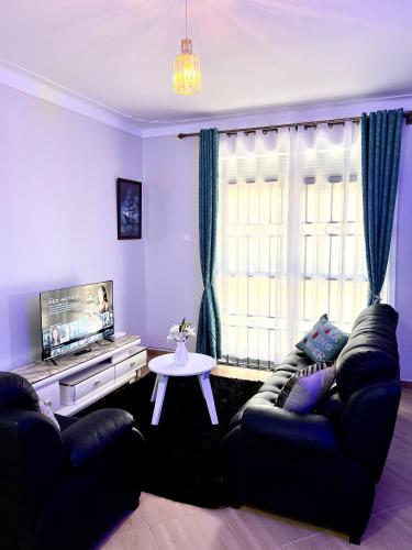 a living room with a couch and a tv at Elvina Home Buziga in Kampala