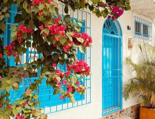 a bunch of flowers on a building with blue windows at El santorini colombiano en Doradal in Puerto Triunfo