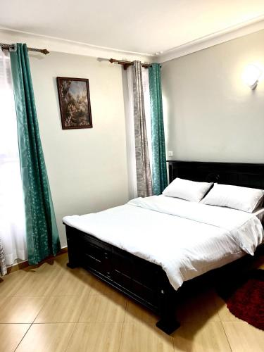 a bedroom with a large bed with green curtains at Elvina Home Buziga in Kampala