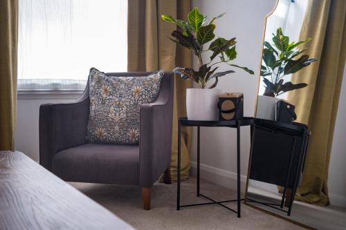 Un dormitorio con una silla y una mesa con una planta en The Artists Loft - Luxury Lake District Apartment with Private Parking, en Kendal