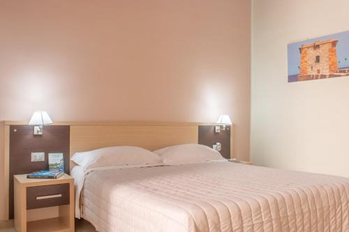 a bedroom with a large white bed and a night stand at Porta delle Botteghelle in Trapani