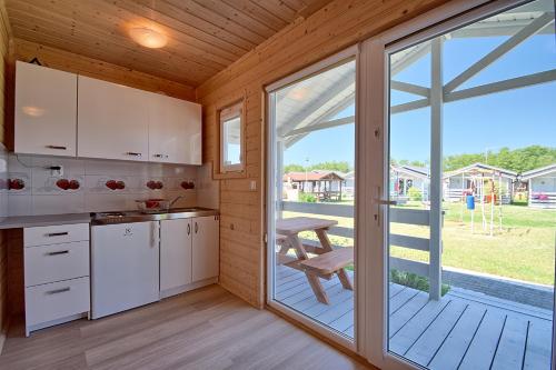 a kitchen with white cabinets and a large sliding glass door at Rumiankowa Polana in Sarbinowo