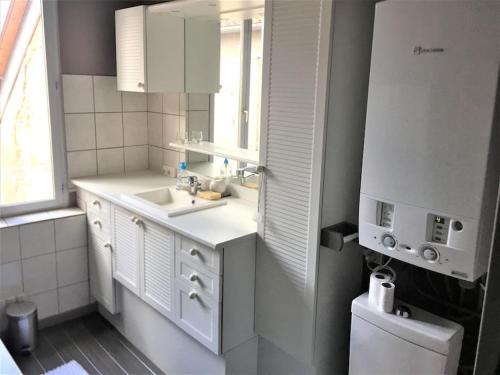 a white bathroom with a sink and a mirror at Appartement 3 pièces pleins de charmes (Virginie) in Montbéliard