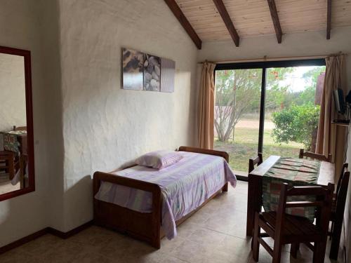 a bedroom with a bed and a table and a window at Casa Picaflor UY in Jaureguiberry