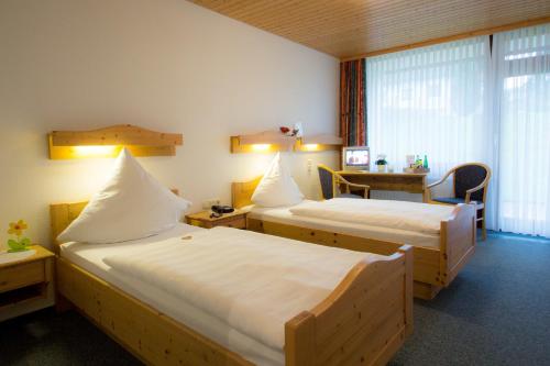 a hotel room with two beds and a table at Hotel Am Lingelbach in Knüllwald