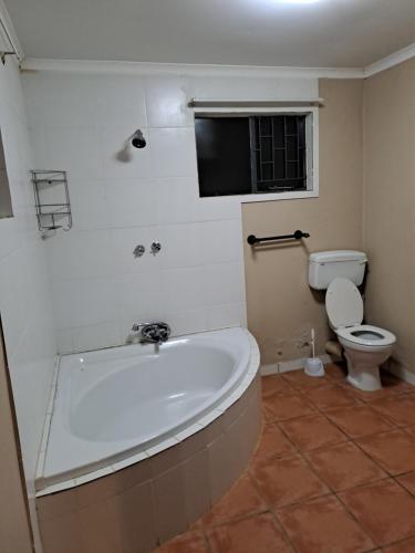 a bathroom with a tub and a toilet and a television at Residential Inn in Pretoria