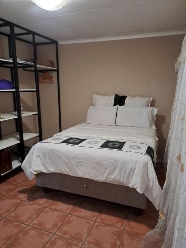 um quarto com uma cama grande com lençóis brancos e almofadas em Residential Inn em Pretoria