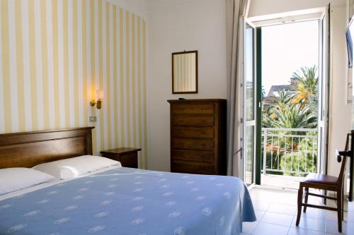 Schlafzimmer mit einem Bett und einer Glasschiebetür in der Unterkunft Hotel Giardino in Follonica