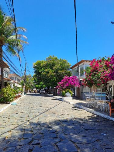 eine Kopfsteinpflasterstraße mit rosa Blumen und Bäumen in der Unterkunft La Coloniale in Búzios