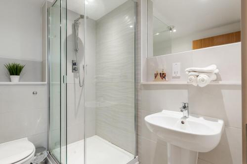 baño blanco con ducha y lavamanos en City Living Penthouse Apartment with Parking (Manchester) en Mánchester