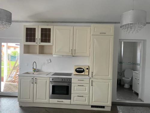 uma cozinha com armários brancos e um forno com placa de fogão em House Of Beyoutiful Bocsa em Bocşa