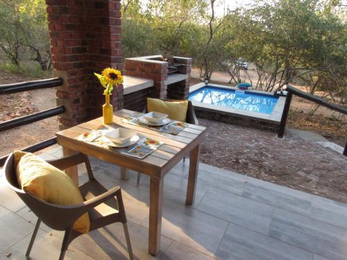 a patio with a table and chairs and a pool at Villa de Leeu, Perfect for Two in Marloth Park