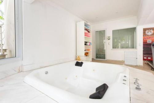 una gran bañera blanca en una habitación blanca en Suites Guarujá Pernambuco, en Guarujá