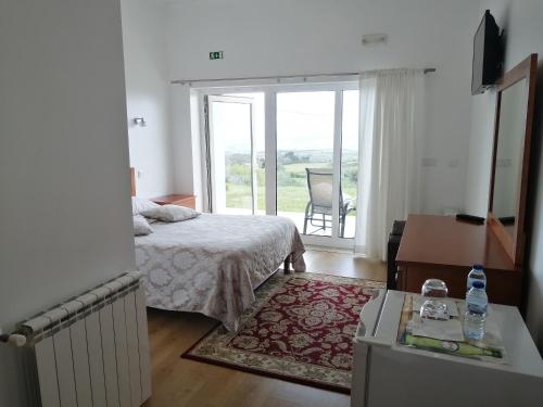 1 dormitorio con cama y vistas a un balcón en Agroturismo A Fidalga, en Linhares