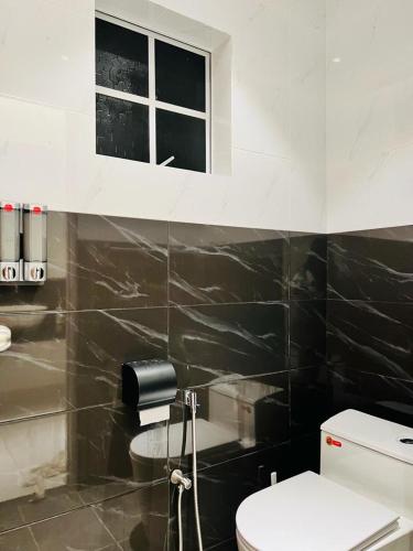 La salle de bains est pourvue de toilettes et d'une fenêtre. dans l'établissement Inn Homestay 1st Floor Unit, à Teluk Intan