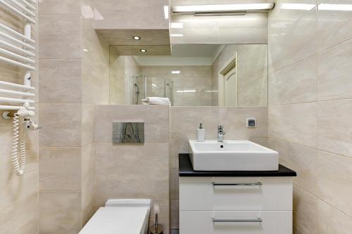 a bathroom with a sink and a toilet and a mirror at Apartament Neptun Park Gdansk Jelitkowo by Grand Apartments in Gdańsk