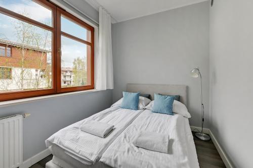 グダニスクにあるApartament Neptun Park Gdansk Jelitkowo by Grand Apartmentsの白いベッドルーム(青い枕の大型ベッド付)
