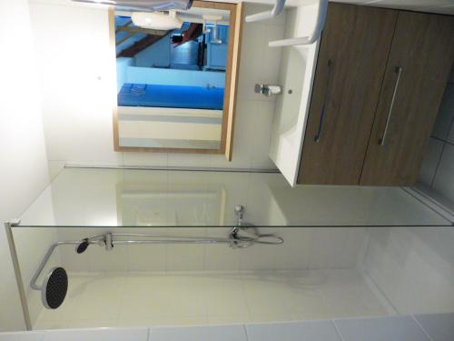 une salle de bain avec un comptoir en verre et un miroir dans l'établissement ALOA Joli 2 Pièces avec mezzanine piscine proche plage Richelieu Cap d'Agde, au Cap d'Agde