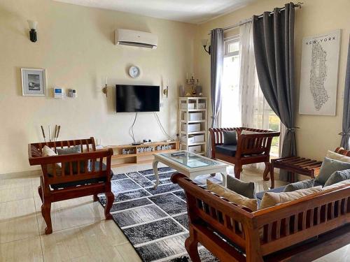 sala de estar con sofá, sillas y TV en Mbweni Raffia Apartment en Kiembi Samaki