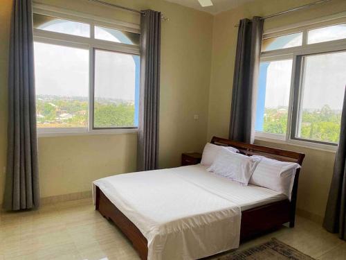 1 dormitorio con 1 cama y 2 ventanas grandes en Mbweni Raffia Apartment en Kiembi Samaki