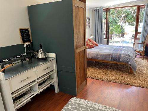 a bedroom with a bed and a dresser with a mirror at Pinchushion Cottage Fish Hoek in Fish hoek