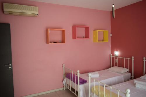 1 dormitorio con 2 camas y pared de color rosa en adonia villa, en Levkákia