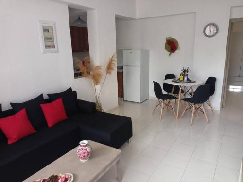 a living room with a black couch and a table at Hibiscus Green Appartments 1 in Afantou