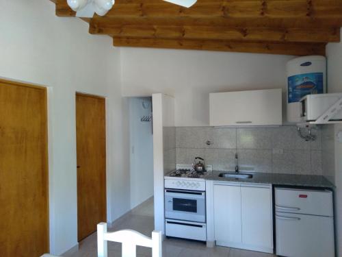 a kitchen with white appliances and a wooden ceiling at Cabañas Ronca Hue in Tandil