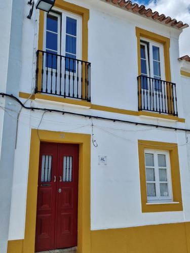 a house with a red door and two windows at The Aqueduct Guesthouse in Évora