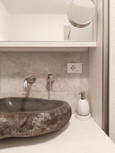 uma casa de banho com um lavatório de pedra e um dispensador de sabão em Apartment Sonne auf Bio-Hof em Merano