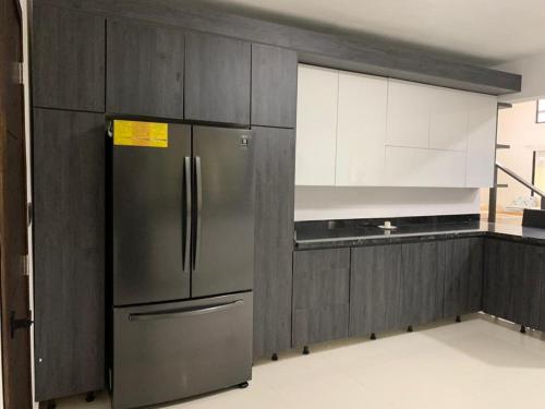 La cuisine est équipée d'un réfrigérateur et de placards en acier inoxydable. dans l'établissement Villa mi paz, à Jarabacoa