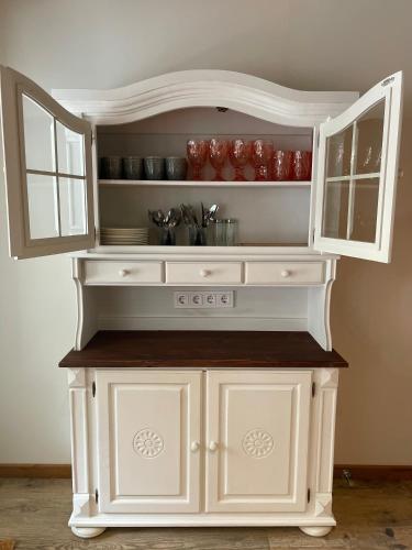 a white cabinet in a kitchen with red dishes at Emakaru Puhkemaja in Otepää