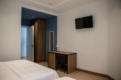 Dormitorio con cama, escritorio y TV en Hotel Blini en Shkodër