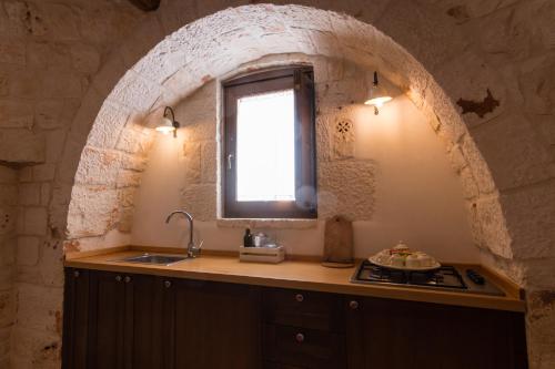 a kitchen with a sink and a window at Almapetra Trulli Resort in Locorotondo