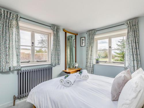 a bedroom with a large white bed with windows at Pass the Keys Beautiful Cottage In South Downs in Chichester