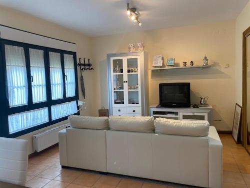 a living room with a white couch and a tv at Apartamentos Las Fuentes in Castropol
