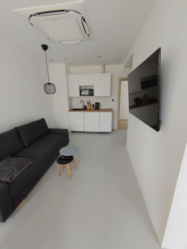 a living room with a black couch and a kitchen at Apartamenty HELIOS in Jastrzębia Góra