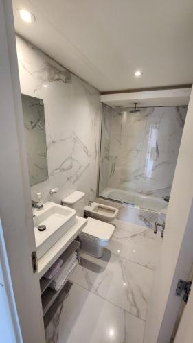 a white bathroom with a sink and a toilet at Departamento Pinamar Centro Status Tower in Pinamar