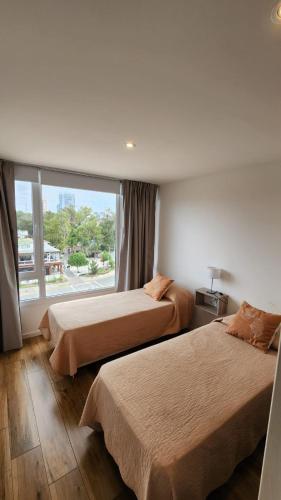 a hotel room with two beds and a window at Departamento Pinamar Centro Status Tower in Pinamar