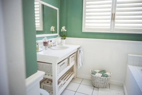 baño con lavabo blanco y pared verde en AirTulla, en Port Elizabeth