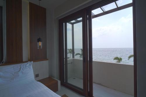 a bedroom with a large window with a view of the ocean at Araya Beach Casas in Batangas City